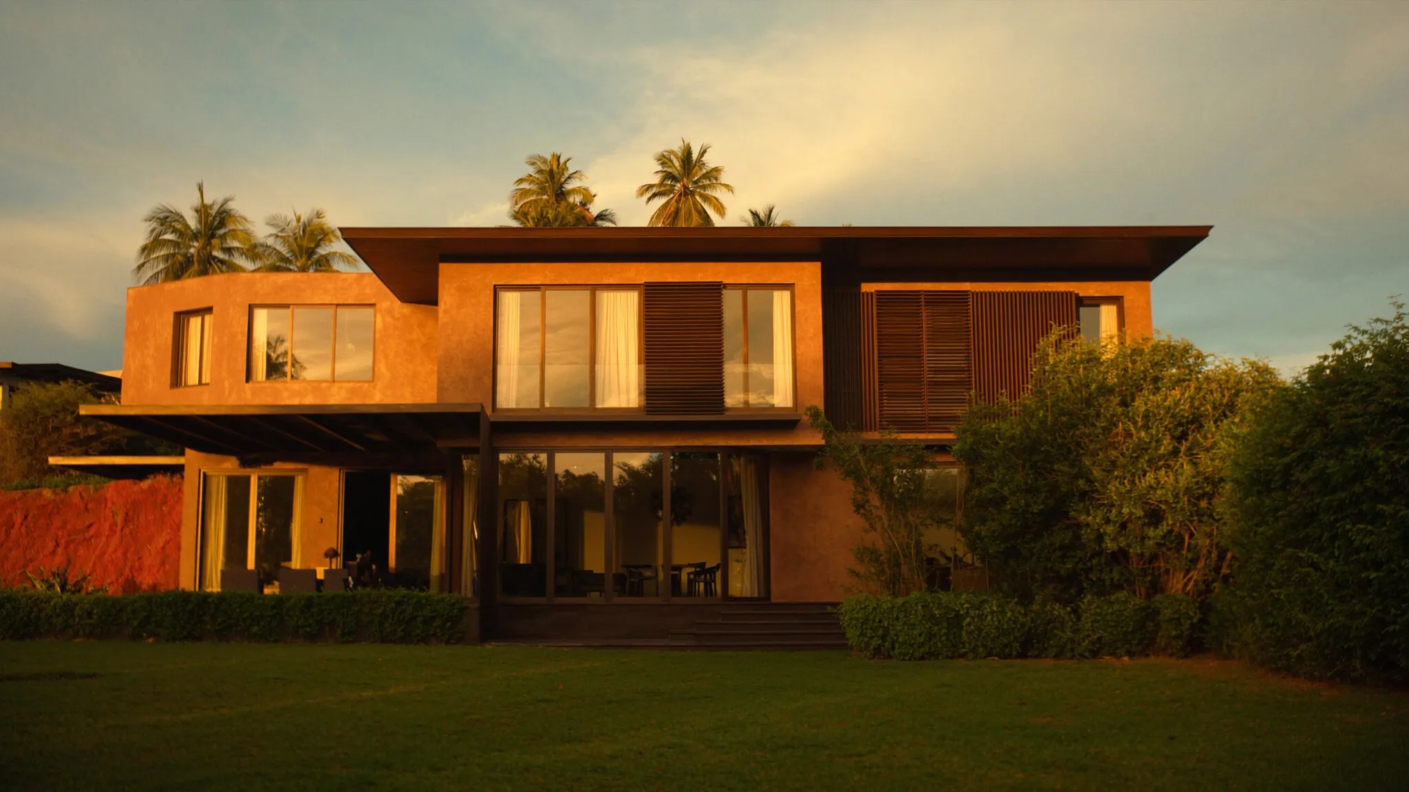 Villa contemporaine au Cameroun à l'heure dorée, murs terracotta et bois.